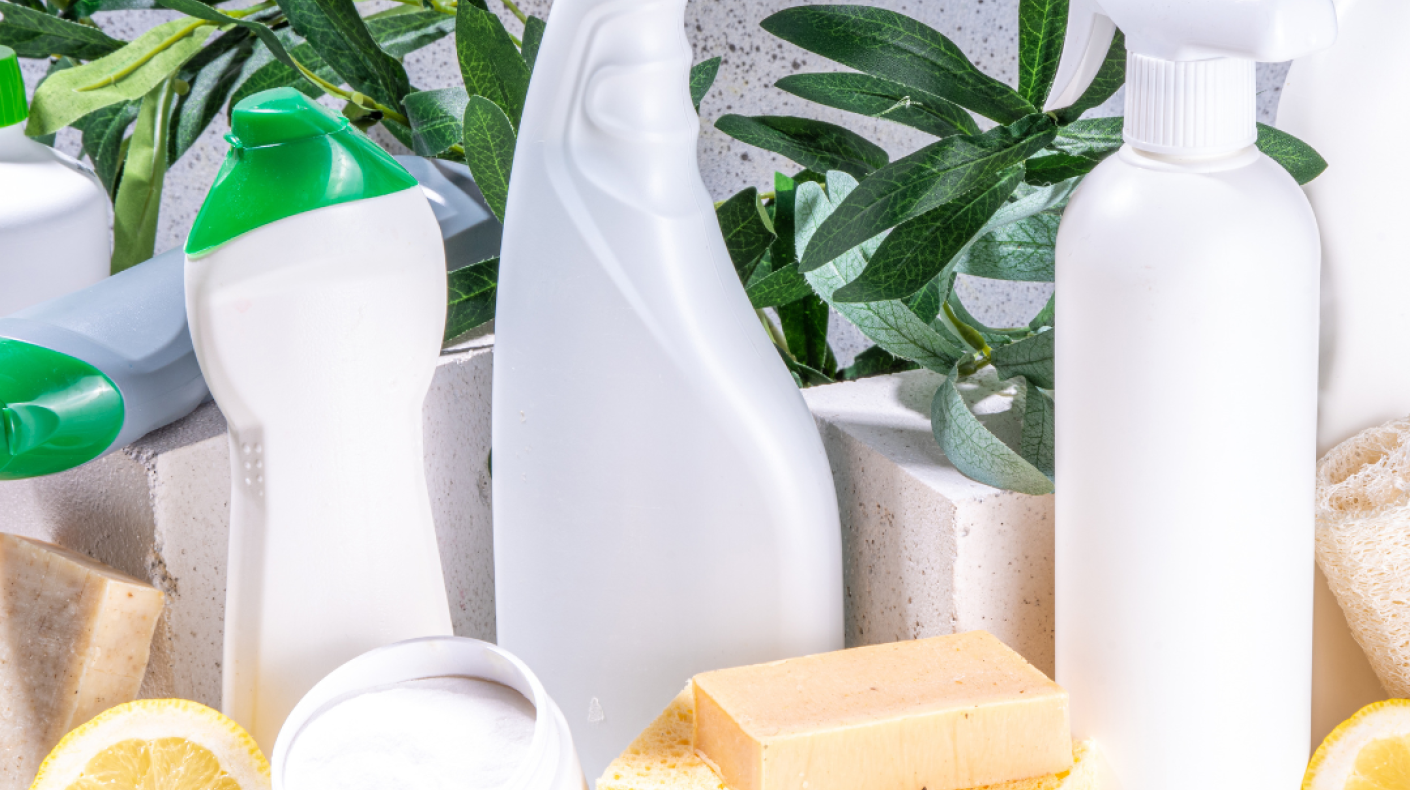 A set of cleaning products in shades of white, yellow and green. There are lemons and plants in the photo as well
