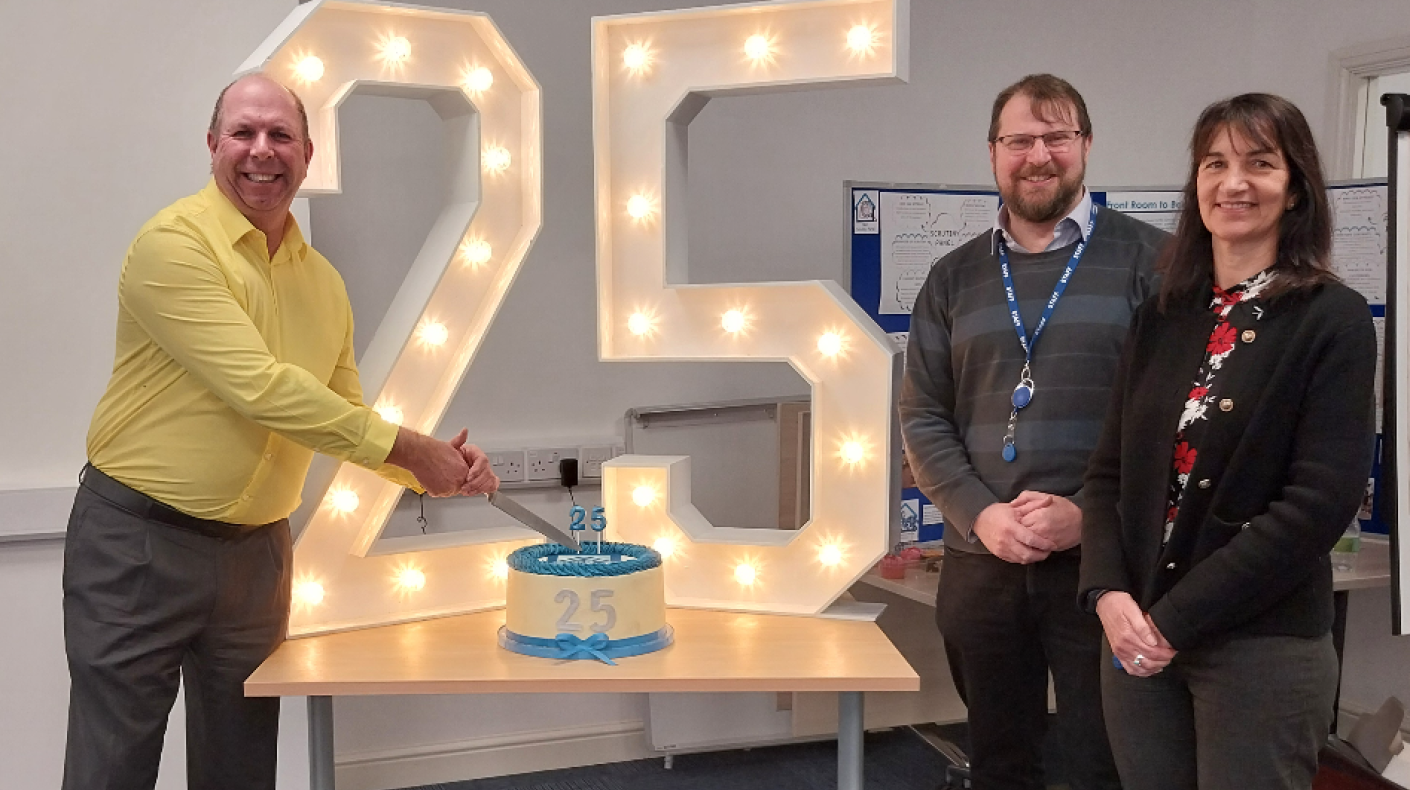 Chief Executive, Martyn Gimber cutting a 25th birthday celebratory cake with Marc Rostock, Director of Neighbourhoods and Philippa Butler, Finance Director