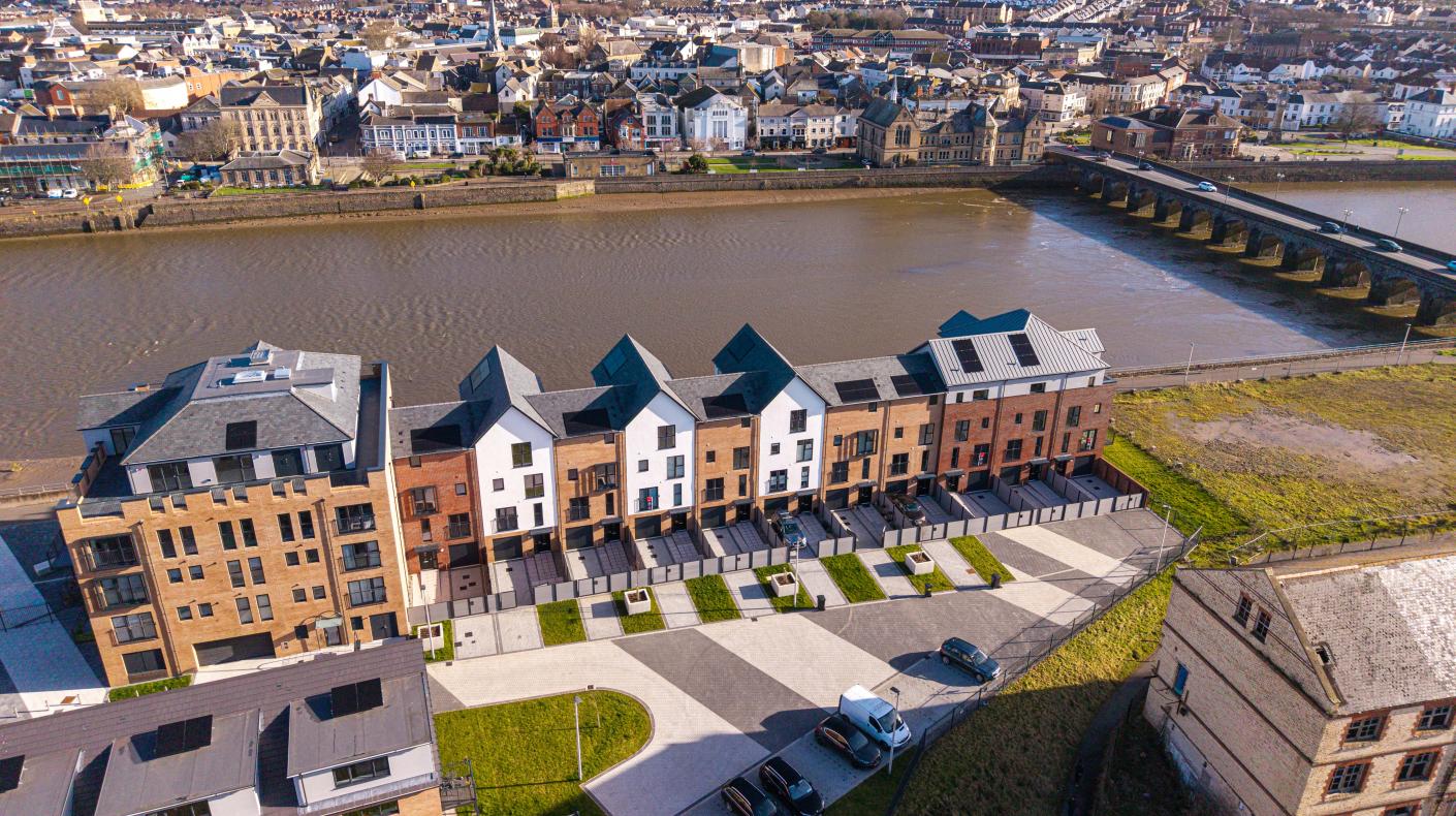 A row of houses next to a river with the rest of the town on the other side