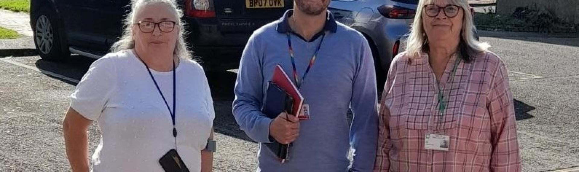 A man stood inbetween two ladies in a car park