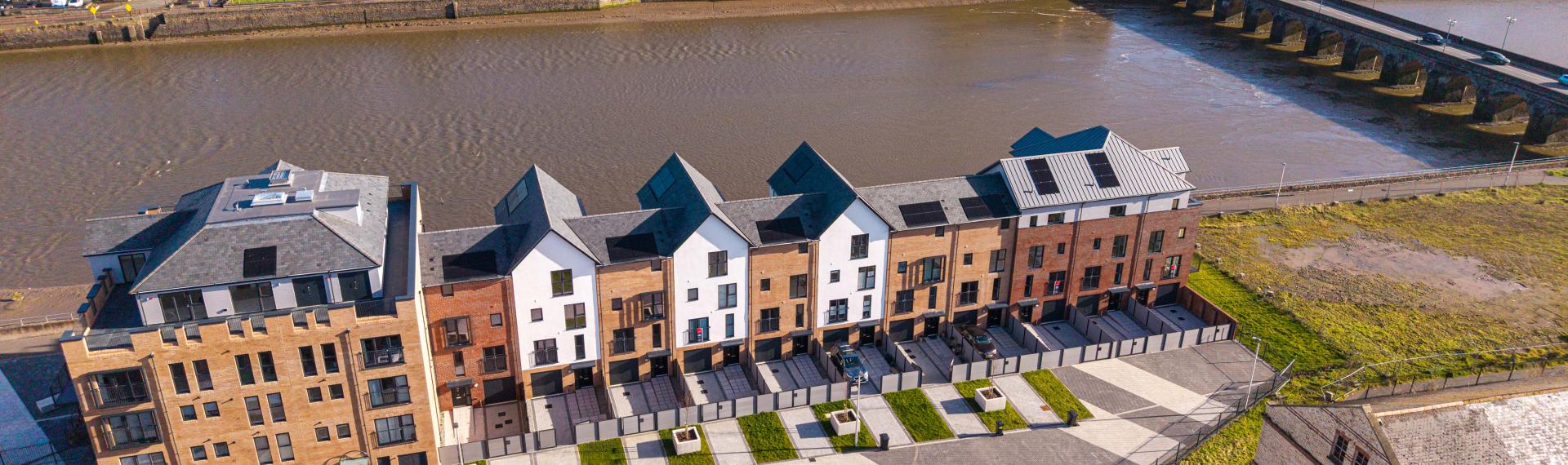 A row of houses next to a river with the rest of the town on the other side