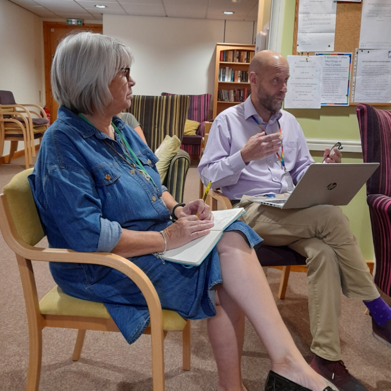 Man and woman sat in wooden chairs