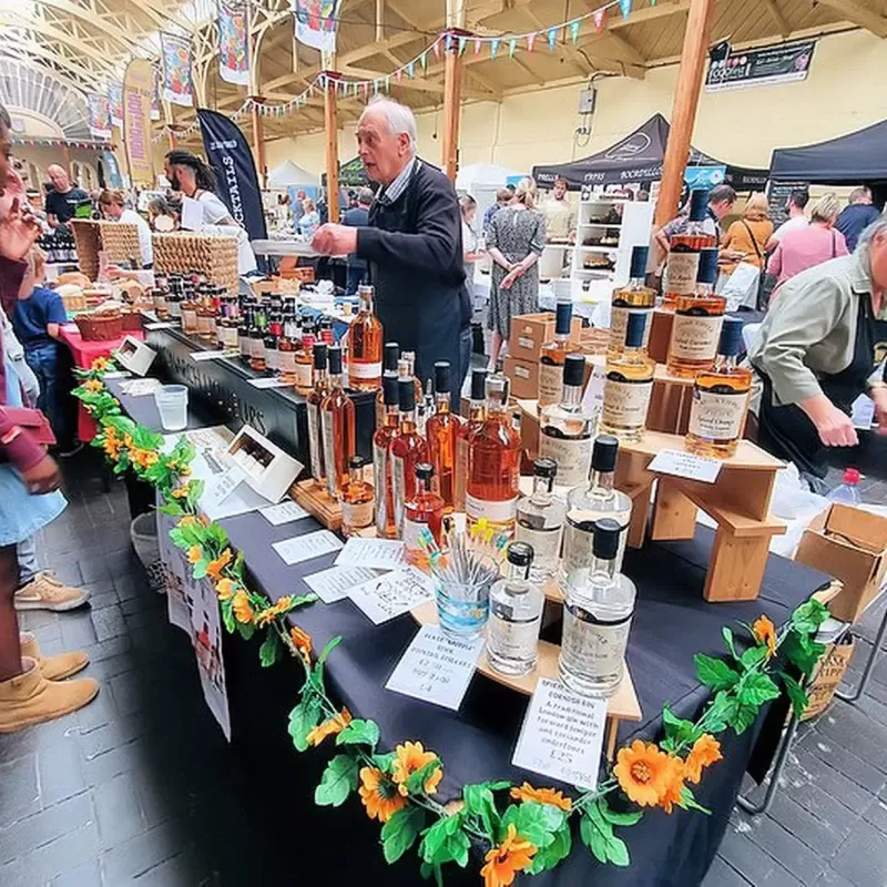 A busy event in a pannier market with many stalls and traders and customers looking to buy