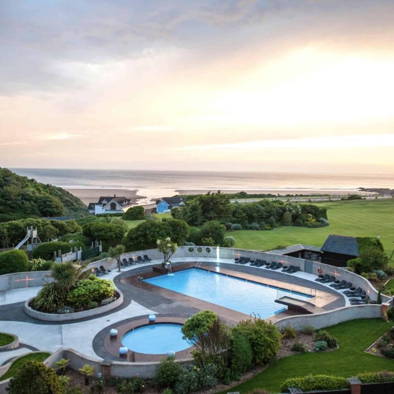 A birds eye view of swimming pools surrounded by grass and the sea