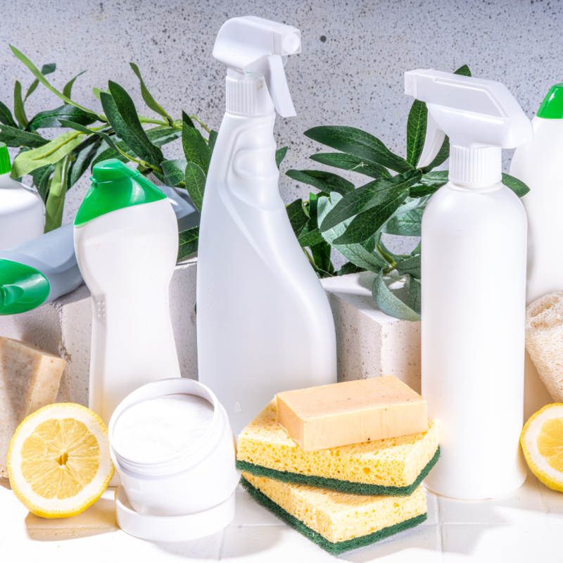 A set of cleaning products in shades of white, yellow and green. There are lemons and plants in the photo as well