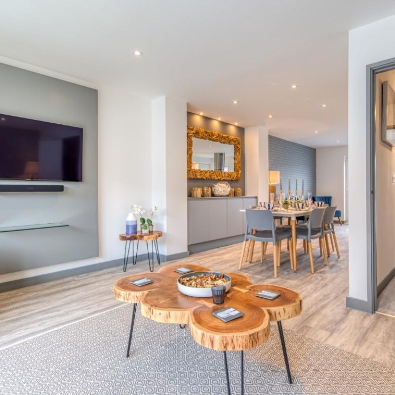 A coffee table and armchair, a wall mounted TV and a dining table in a showhome