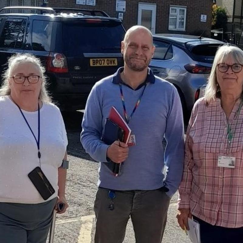 A man stood inbetween two ladies in a car park