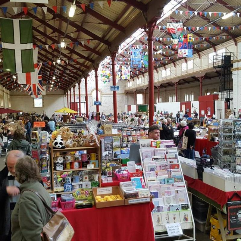 A busy event in a pannier market with many stalls and traders and customers looking to buy