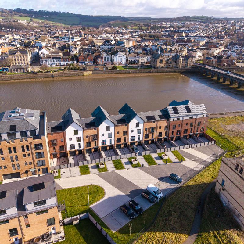 A row of houses next to a river with the rest of the town on the other side